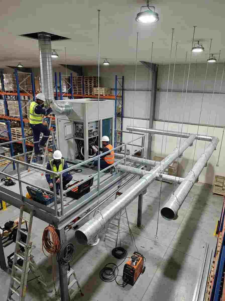 HVAC technicians installing a 10-ton ducted AC system with spiral ductwork in an Al Quoz warehouse