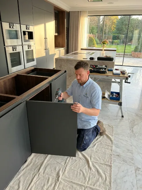 Carpenter fitting a dark grey kitchen cabinet panel during a modern kitchen renovation.