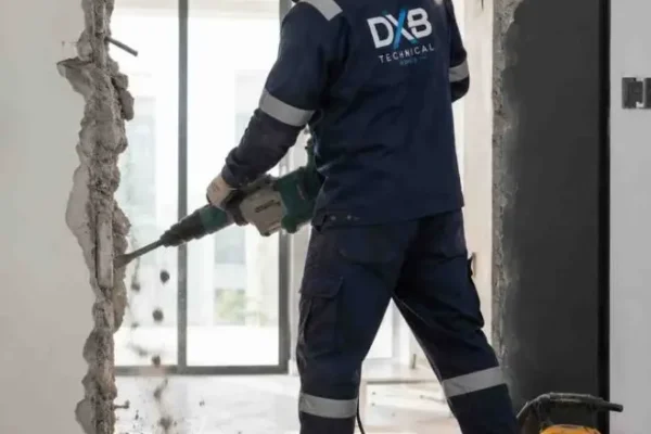 Professional demolition Worker from dubai technical works carefully and with safety guidlines demoloshing the wall with machine look professional demolishing service in dubai